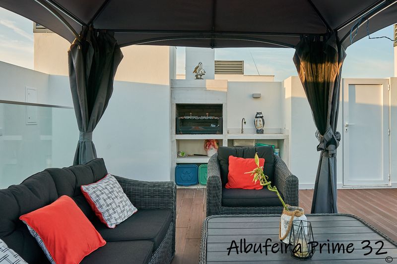 Covered lounge seating beside the built-in barbecue on the roof terrace